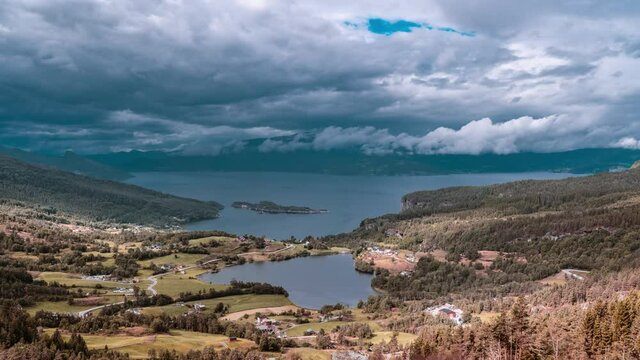 Thick heavy clouds are moving over a peaceful haven on Hardangerfjord. Numerous houses are scattered along the shore and deeper into the valley. A few rural roads connecting the bay with the mainland.