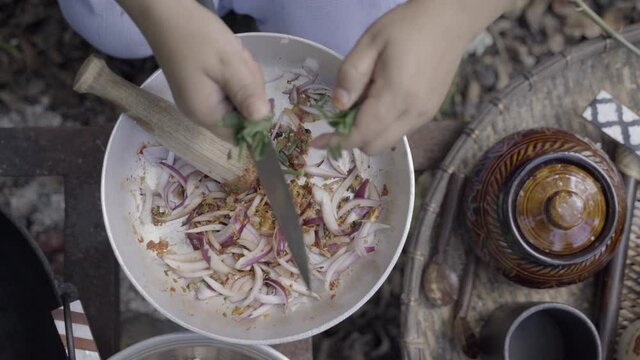 Green onions are cut with knife into bowl with raw chutney vegetables