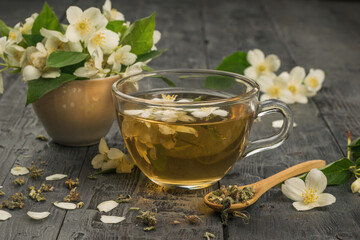 A cup of jasmine tea and jasmine flowers on a wooden table.