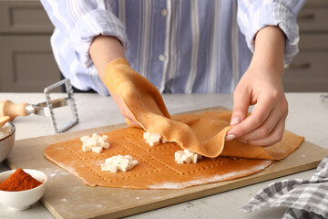 Female chef making delicious ravioli at table, closeup