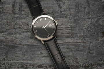 Men's watch with hands on a wooden background.