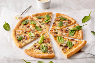 Slices of vegetarian pizza with spinach and mushrooms on light table