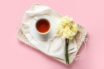 Tray with cup of tea and beautiful narcissus flowers on color background