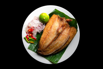 Thai food. Deep fried Snake head fish with Chili, lemon and red onion in white plate, isolated on a black background