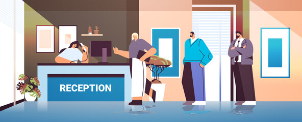 business people customers or travelers standing at reception desk and talking to receptionist