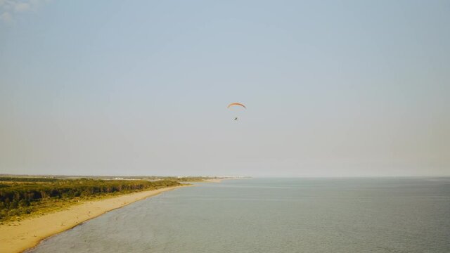 Brussa empty beach and paraglider paragliding, aerial circling. Italy