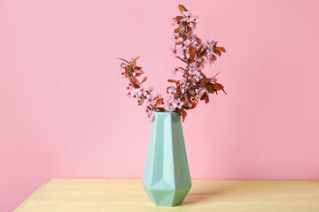 Vase with beautiful blossoming branches on color background