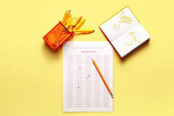 Answer sheet, stationery and notebook with text EXAMS on color background