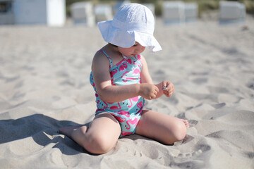 Little happy girl on white sand beach enjoying summer and vacation