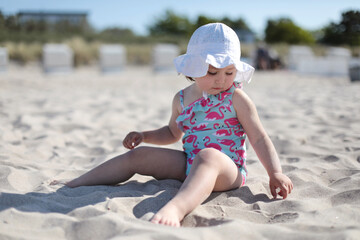 Little happy girl playing on white sand beach