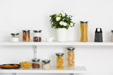 Beautiful roses in pot and food on shelf in kitchen