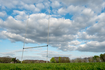 Fototapeta na wymiar Tall goal posts for Irish national sports, camogie, hurling, Gaelic football, soccer and rugby. Warm sunny day. Blue cloudy sky. Extremely low angle of view