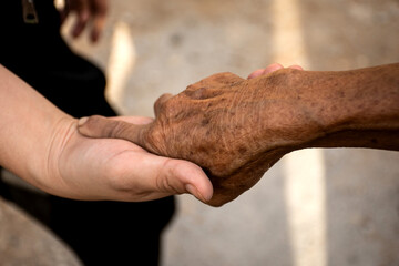 Young woman hand holding elderly person's hand.