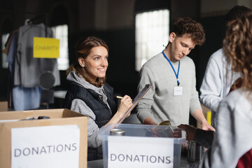 Group of volunteers working in community charity donation center., sorting out clothes and canned...