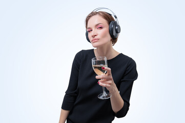 Portrait of a woman in professional headphones with a glass of wine in her hand. White background....