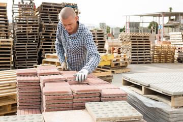 Worker places paving slabs on a pallet in a building materials warehouse