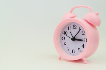 Pink alarm clock on gray background, large space for text.