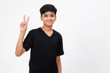 Enthusiastic young India boy raises his fingers showing victory sign. Cute teenager raising his arms in delight