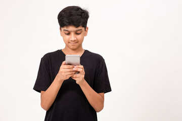 Young Indian boy using mobile phone. Cute teenager checks social media on phone
