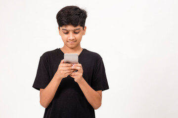 Young Indian boy using mobile phone. Cute teenager checks social media on phone © Bhaven