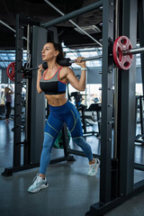 Fototapeta na wymiar Woman doing reverse lunges on Smith machine at gym