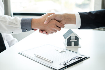 Fototapeta na wymiar Businessmen and brokers' real estate agents shake hands after completing negotiations to buy houses insurance and sign contracts. Home insurance concept