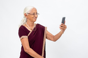 Mature Indian lady takes a selfie from her phone. Senior woman using her mobile phone to take a photo.