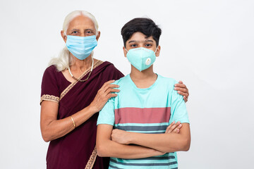 Young Indian boy stands with his grand mother both wearing Covd-19 protection mask, Senior Indian female with her grandson.