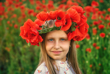 Portrait of a beautiful little girl in a wreath of field poppies