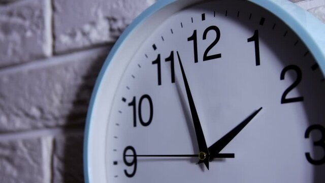 Round office clock shows five minutes to two. Business and time concept - wall clock over white