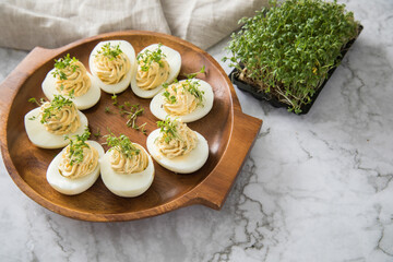 Kalte gefüllte russische Eier mit Frischkäse, Kresse und Kräuter farciert auf Holz Eierteller,...