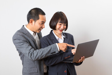 Asian businesswoman and businessman holding computer standing on white background.