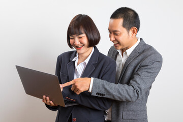 Asian businesswoman and businessman holding computer standing on white background.