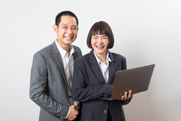 Asian businesswoman and businessman holding computer standing on white background.