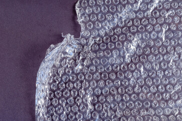 Protective bubble wrap on colored background. Texture of plastic wrap with carelessly torn edge.