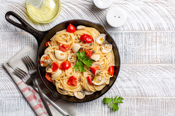 Spaghetti with vongole or clams, tomato and parsley, italian pasta with seafood. Light wood...