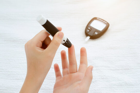 Child Hands Using Lancet on Finger to Check Blood Sugar Level by Glucometer.