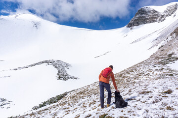 Fototapeta na wymiar Young man with black dog looks at the mountains. Carpathian mountains, Ukraine