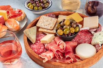 Italian antipasti or Spanish tapas with wine. Charcuterie platter with prosciutto, jamon, cheese, salami, salmon sandwiches and olives. Mediterranean delicattessen
