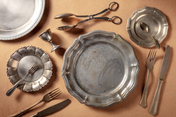 Vintage silver tableware, overhead flat lay shot on a rustic background. Many different plates and...