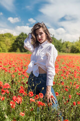 young woman in hat walk at poppy field pick flowers