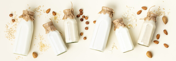 Non dairy plant based milk in bottles and ingredients on light background. Alternative lactose free...