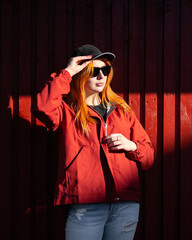 Red haired young woman with sunglasses looking at sun. Red color, Models on monochrome	