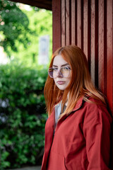 Street portrait of a young red haired woman with transparent sunglasses, monochrome	