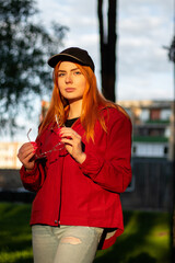 Street portrait of a young red haired woman with sunglasses during a golden hour