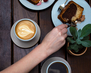 A cup of coffee with a cake and plant in the coffee shop