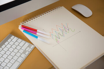 Drawing a graph of growth in a notebook on your desk at home.Wooden work table
