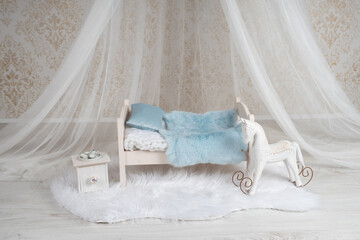 Fototapeta na wymiar Newborn baby bed with a tiny table and a rocking horse in a photo studio