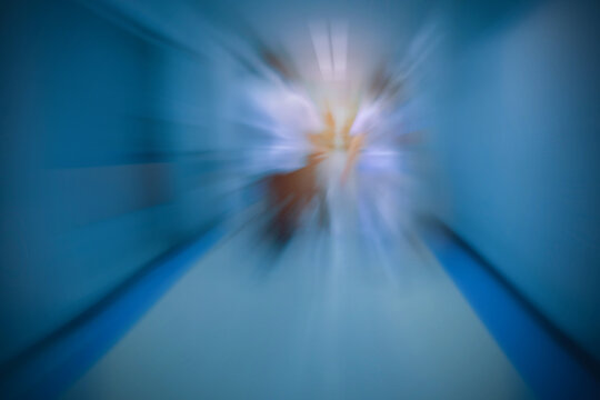 Man and woman assistant nurse taking a patient sitting on wheelchair to the doctor in a hurry. Background process with zoom out effect