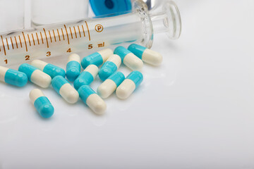 Many capsule pills and drug Syringe on white background